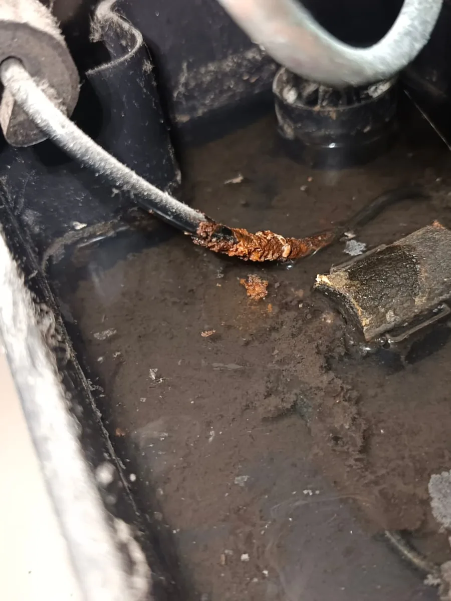 Pieza con óxido dentro de una bandeja oscura con agua y suciedad