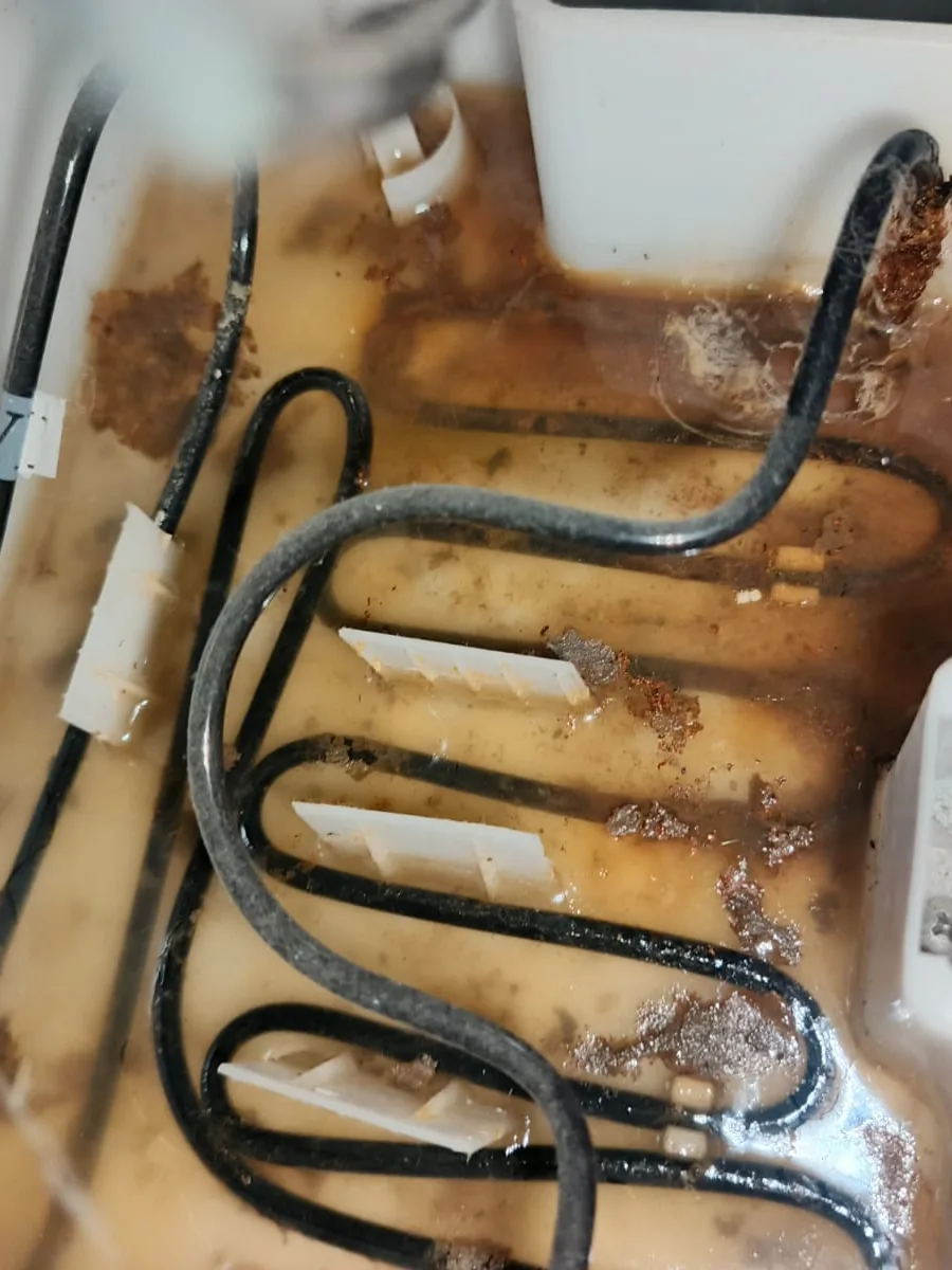 Pieza negra doblada en zigzag dentro de una bandeja blanca con residuos marrones