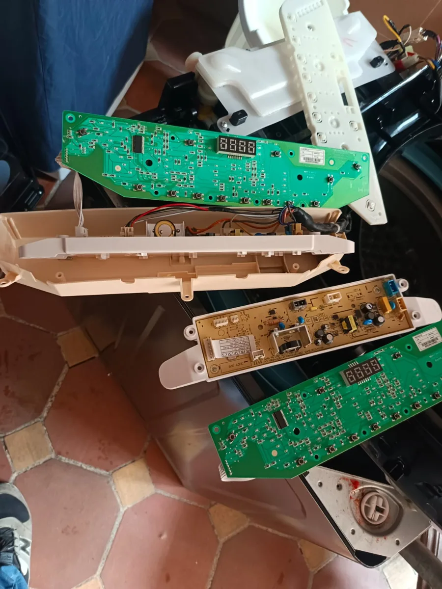 Tarjetas electrónicas y carcasa del panel de una lavadora desmontadas, sobre el equipo