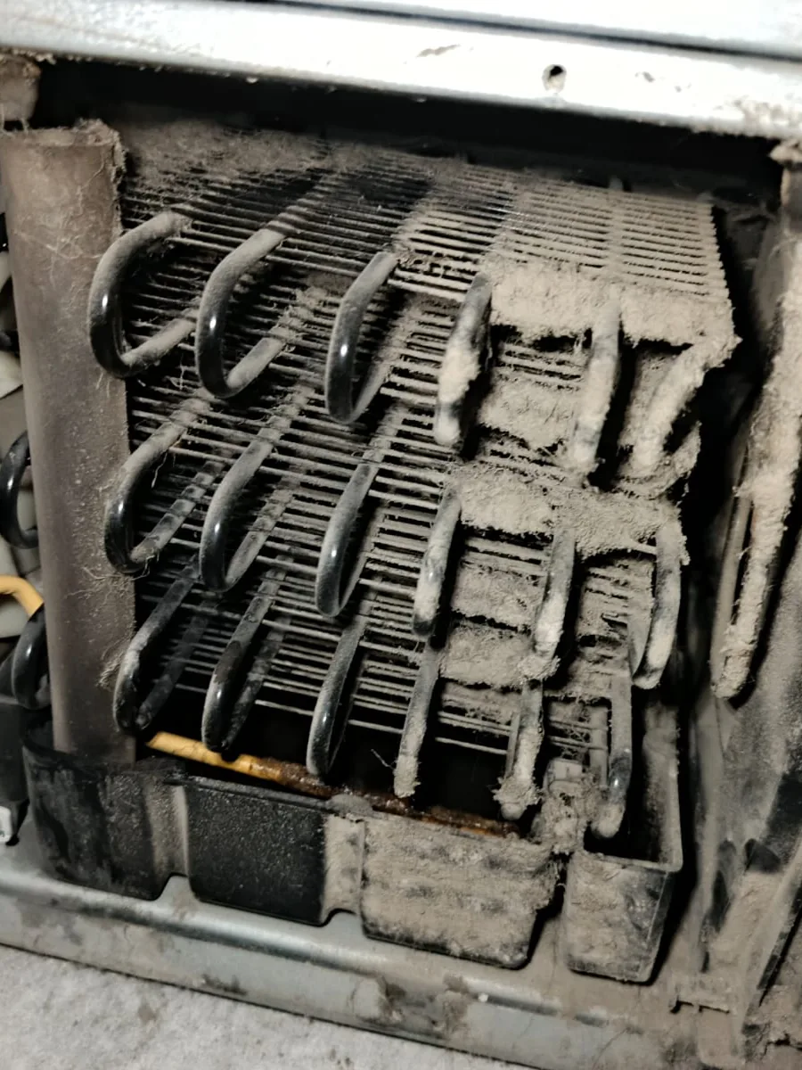 Tubos metálicos y aletas cubiertos de polvo, con las aspas blancas de un ventilador a la izquierda
